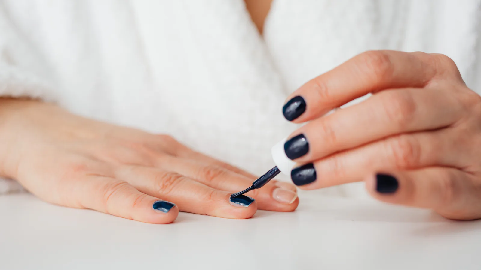 Short, well-kept press-on nails on a hand in daylight, a length that holds through a work week