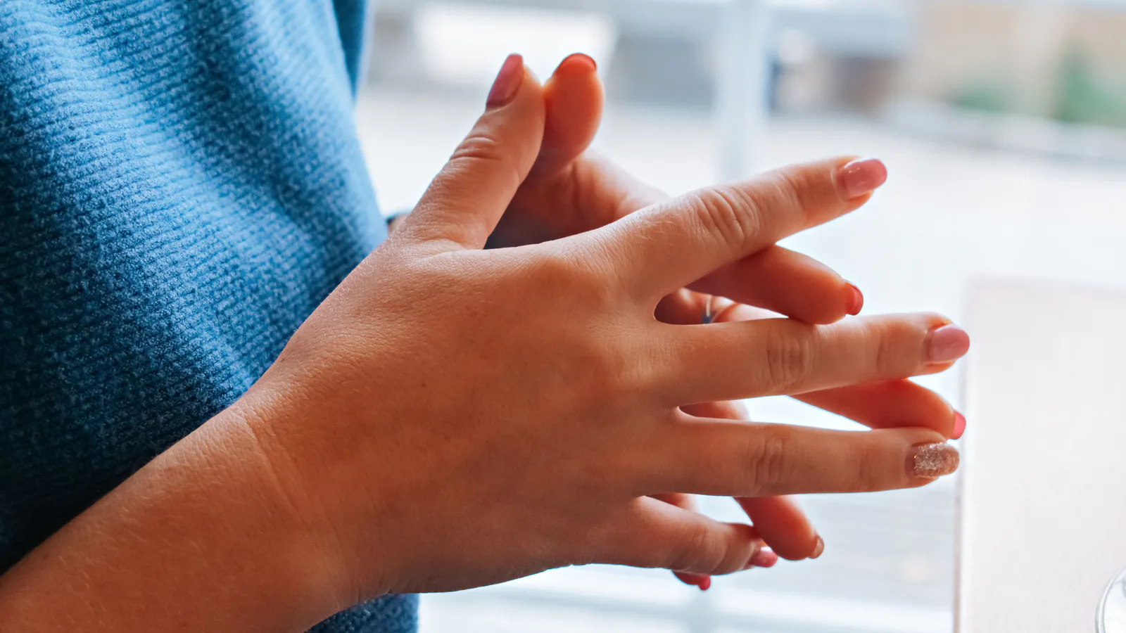 Close-up of short, natural press-on nails on two hands, clean shape with no long free edge